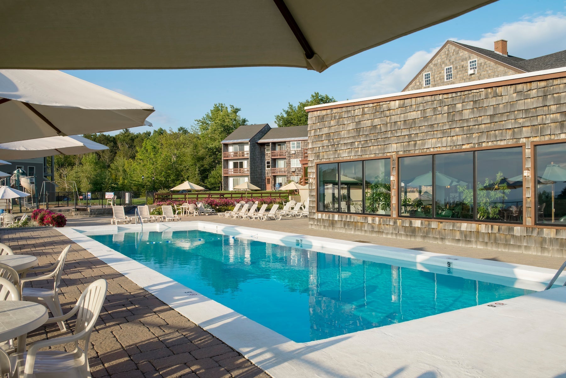 Rectangular outdoor pool at Steele Hill with lounge chairs beside the shingled guest buildings