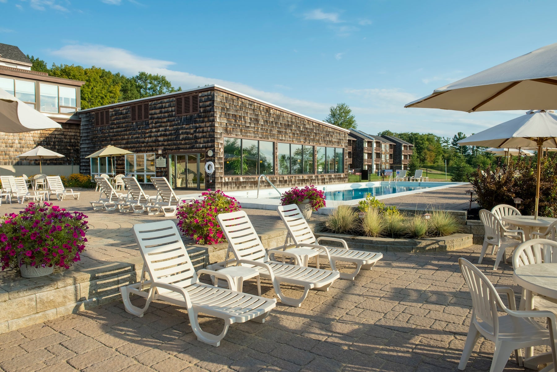 Steele Hill outdoor pool patio with white lounge chairs, umbrellas and flower planters