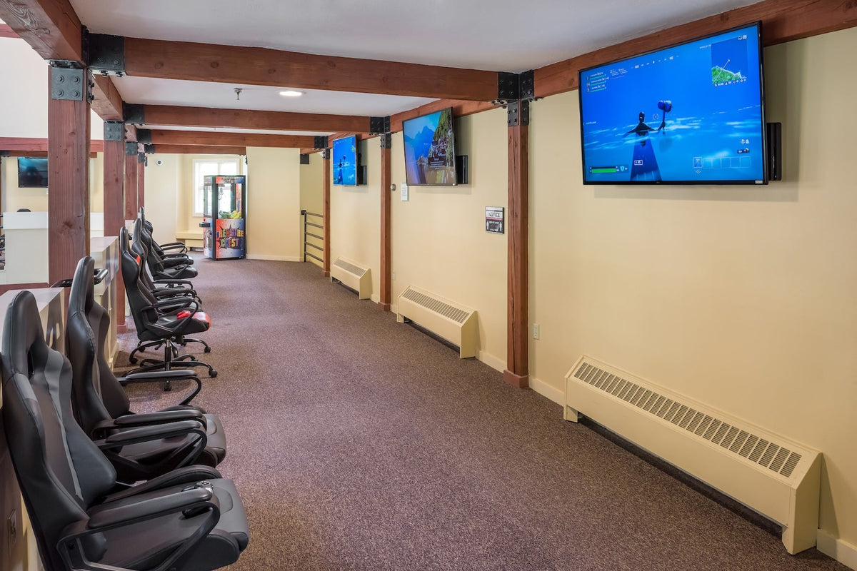 Steele Hill gaming room lined with racing-style chairs facing wall-mounted screens