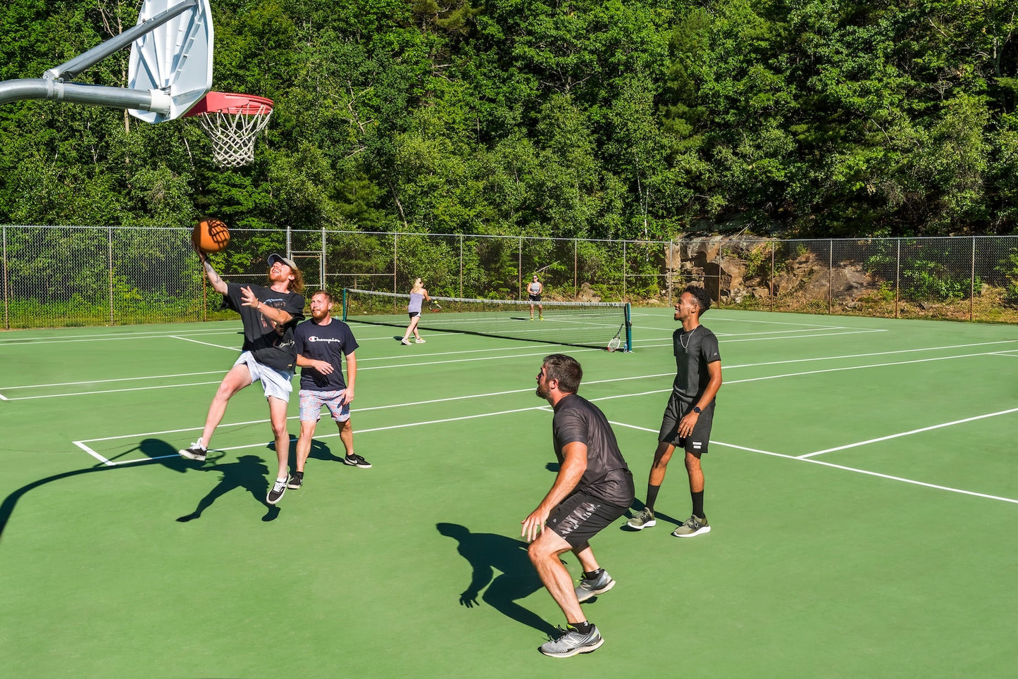 Guests playing pickup basketball on the outdoor court at Steele Hill with tennis courts behind