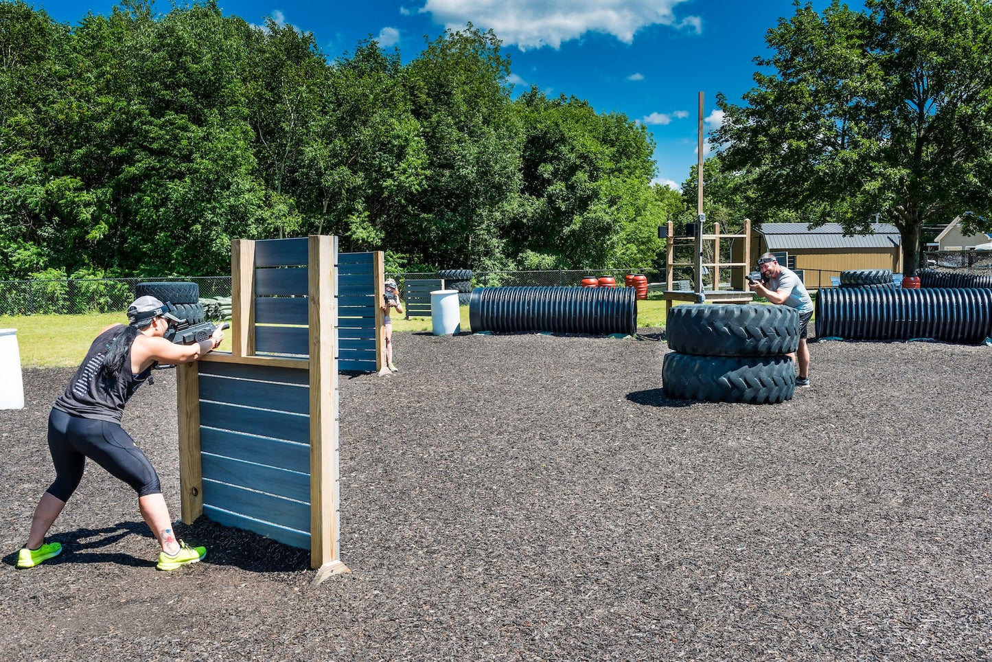 Players crouching behind wooden barriers on the outdoor laser tag field at Steele Hill