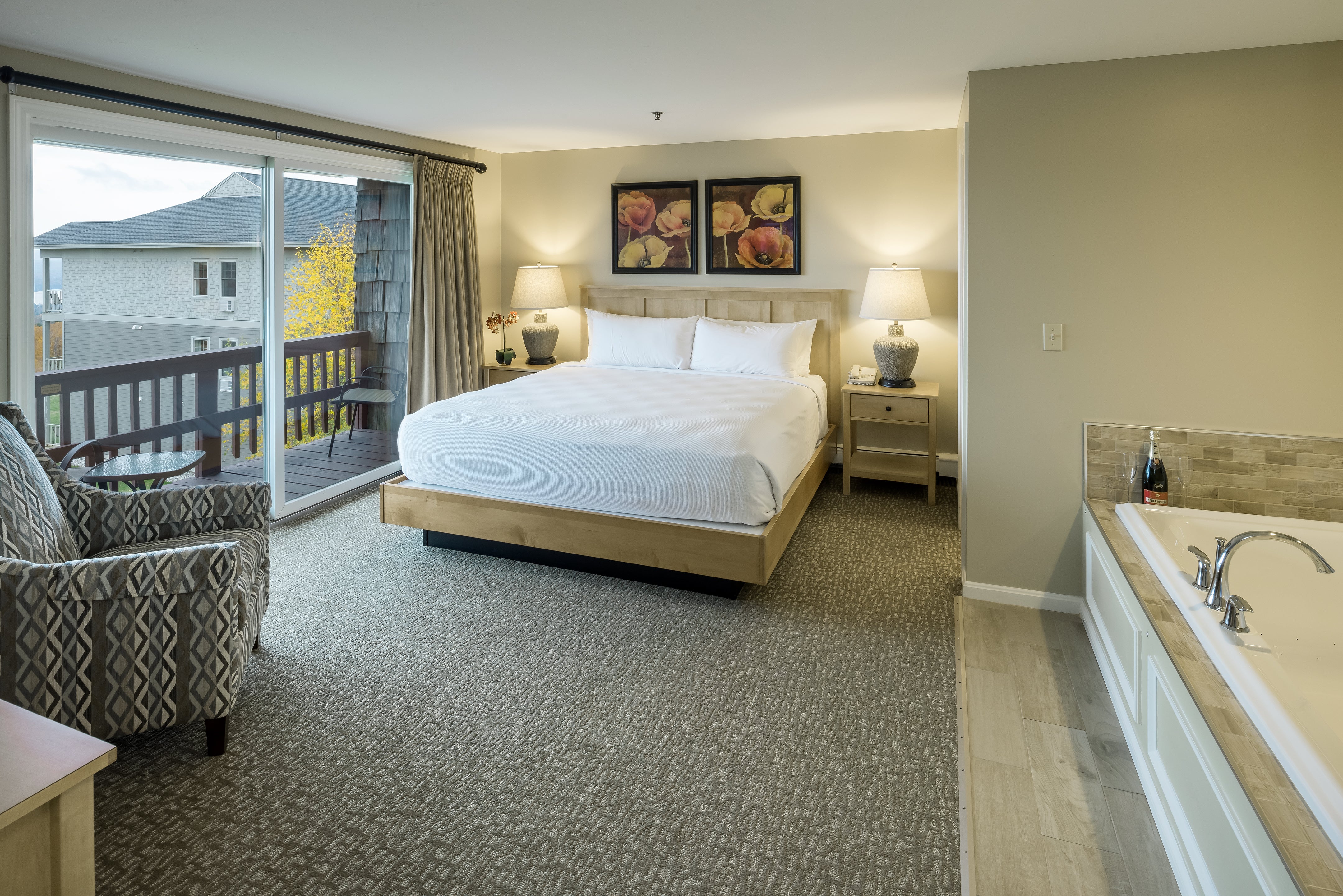 King guest room with a balcony, framed poppy prints and a corner jetted tub with champagne