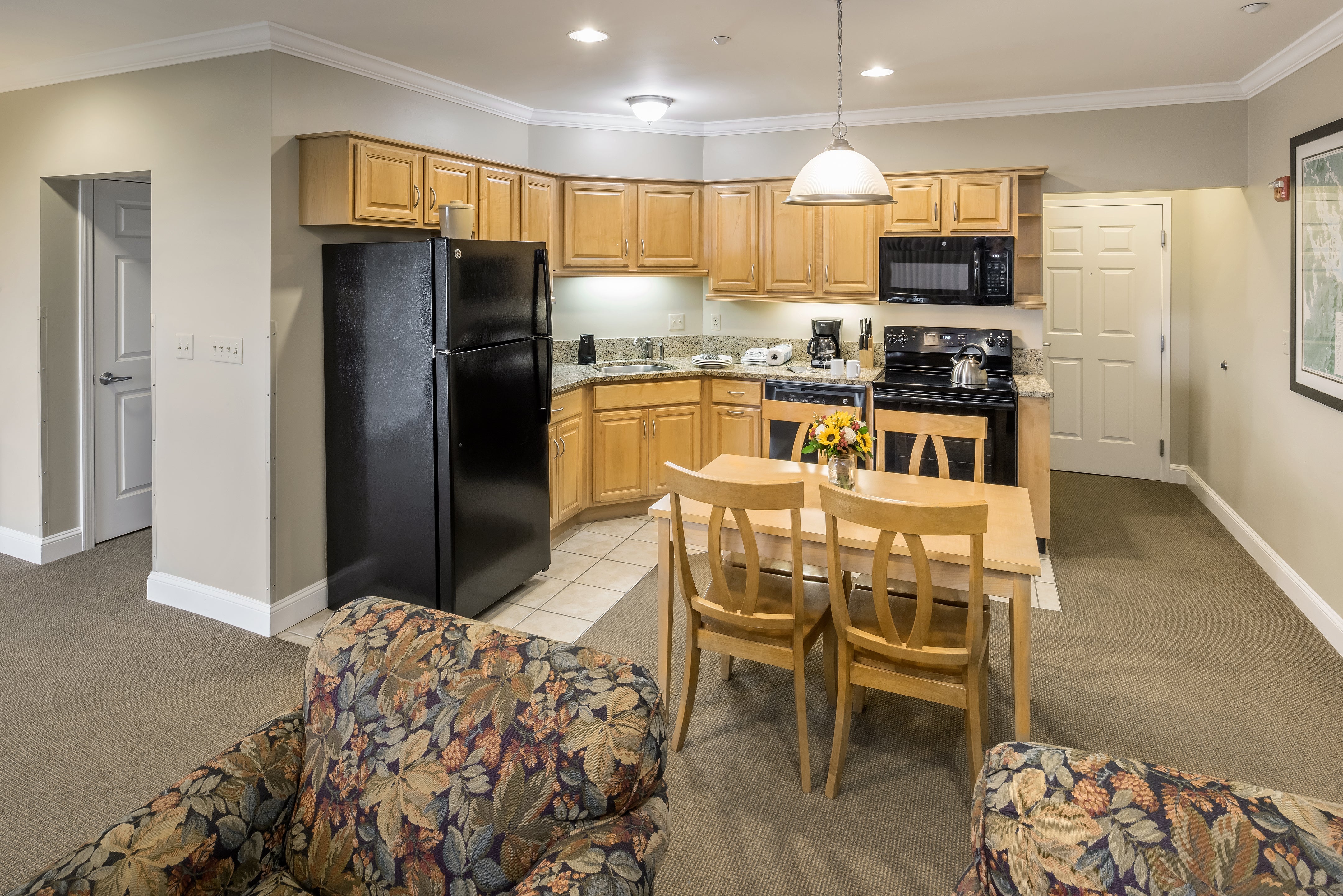 Steele Hill suite kitchen with light oak cabinets, black appliances and a small dining table
