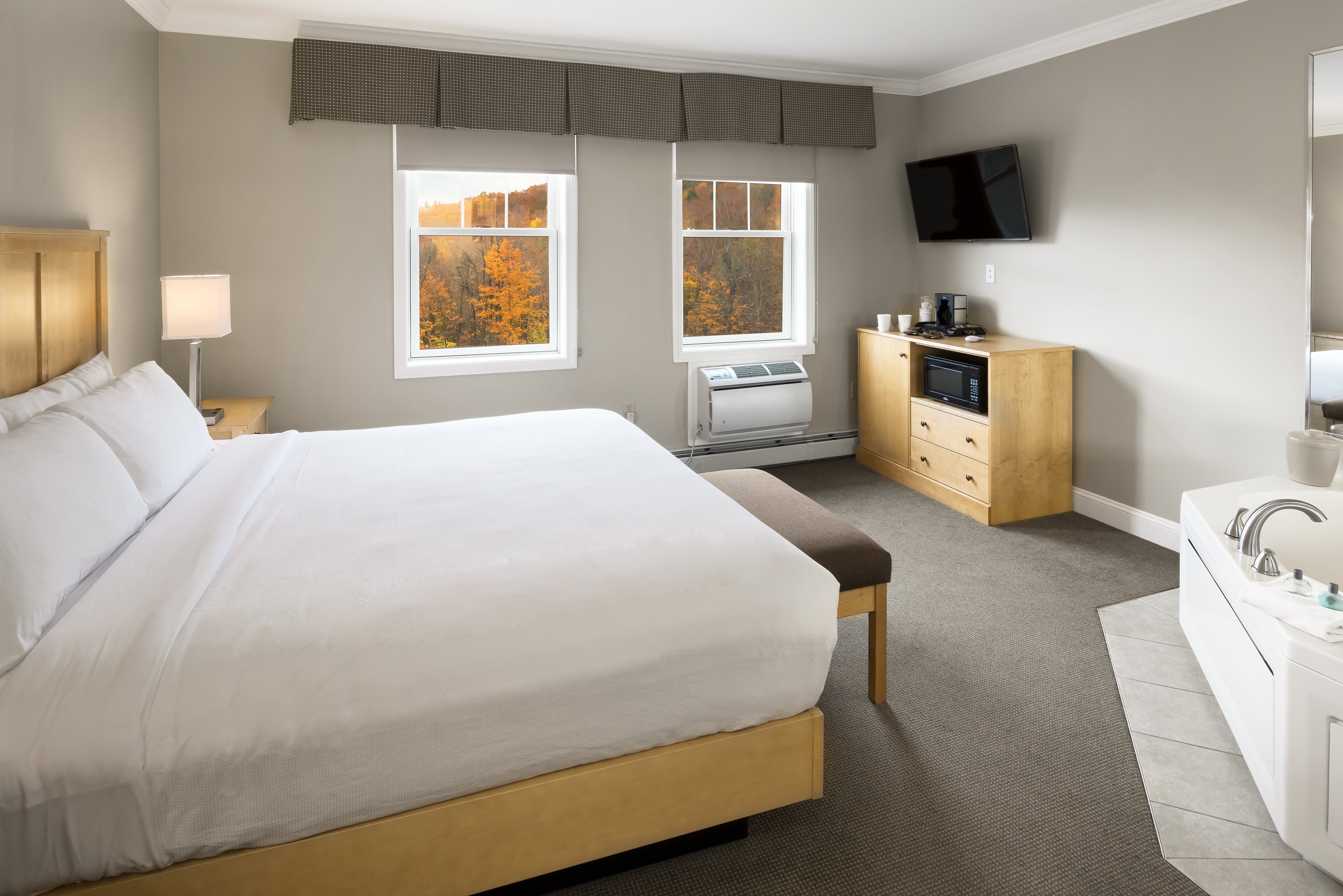 Steele Hill bedroom with a king bed, coffee and microwave station and a jacuzzi tub below fall windows