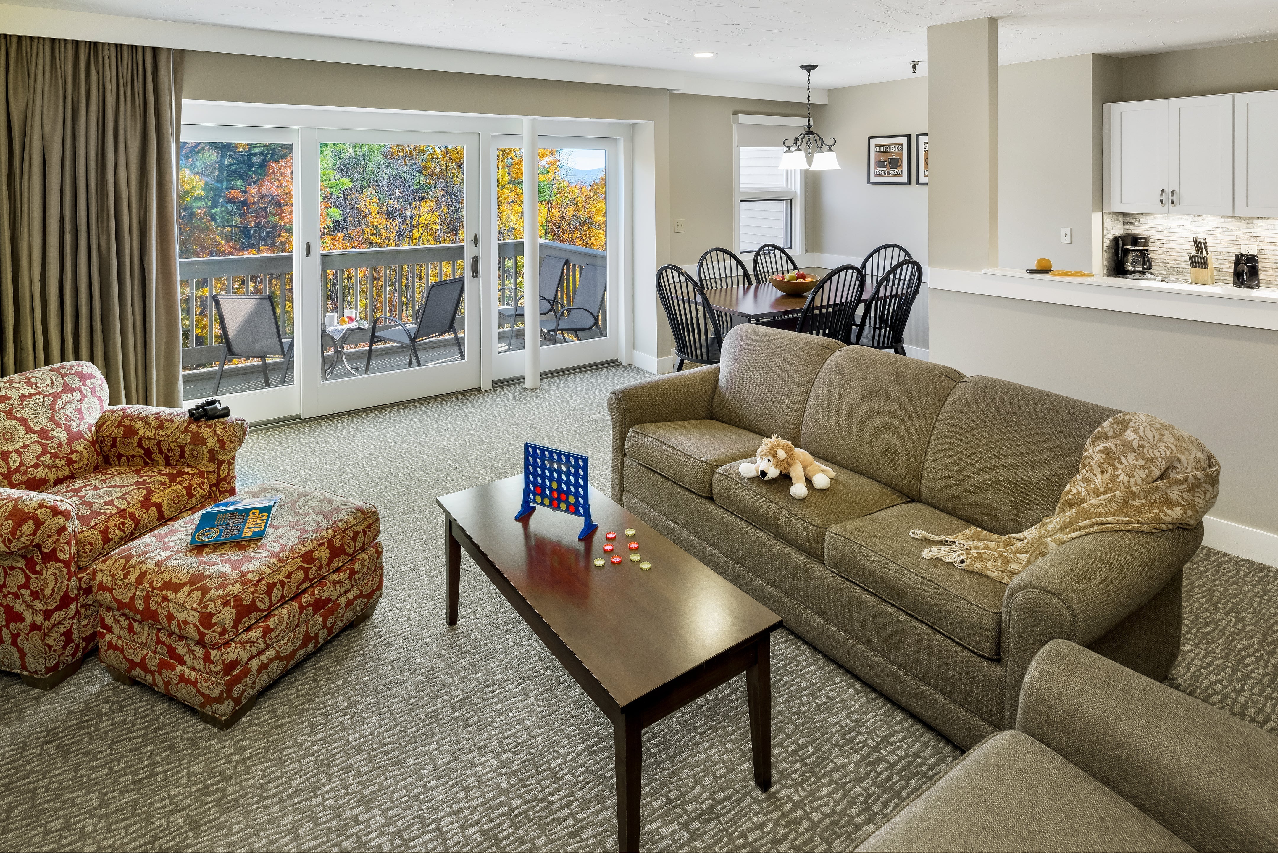 Steele Hill suite living room with sofas, a Connect Four game and balcony doors to autumn foliage