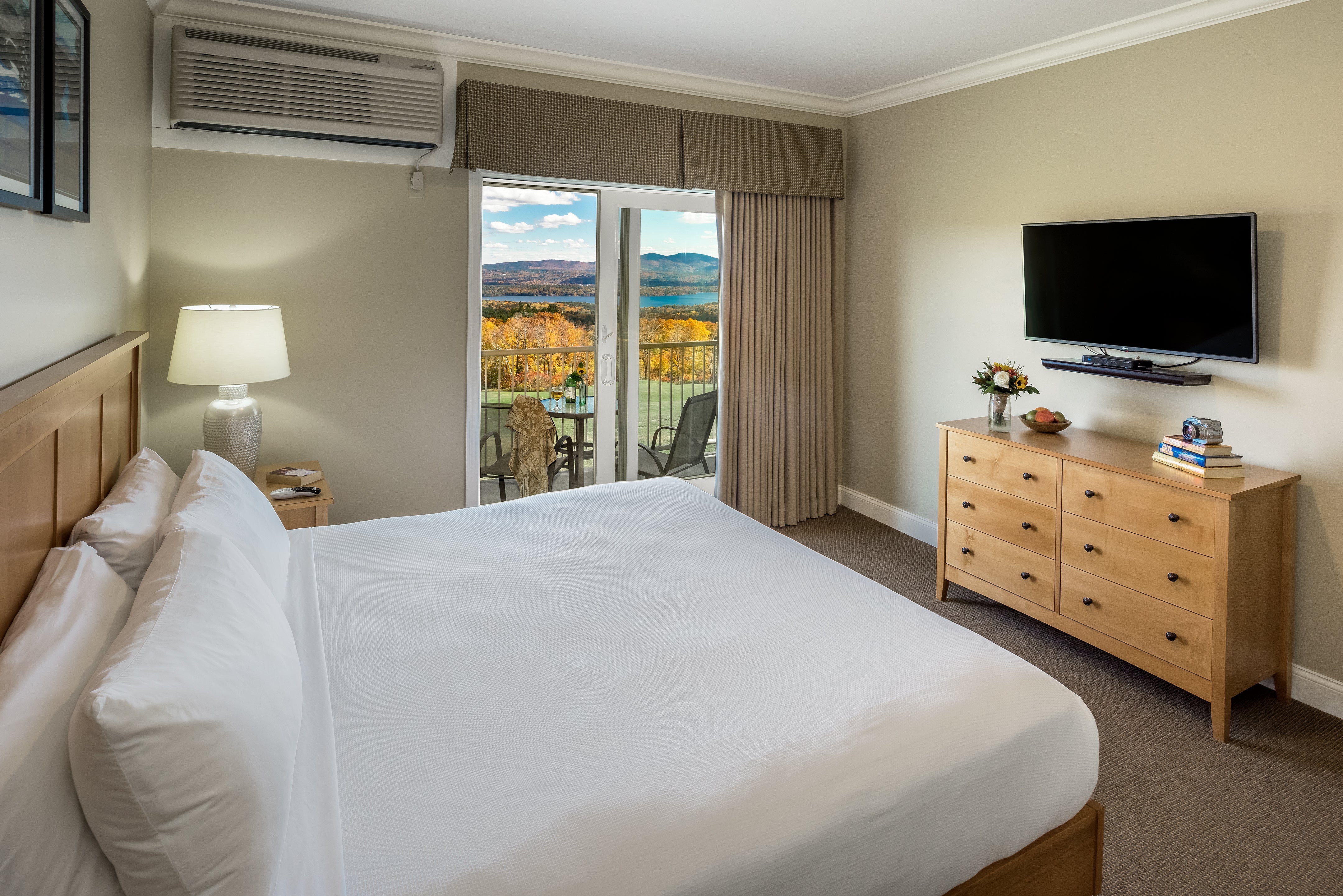 Steele Hill king room with a sliding door to a balcony over autumn foliage, lake and mountains