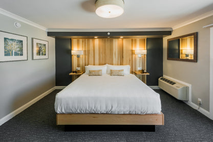 Center Harbor Inn guest room with a king bed, wood-slat headboard wall and framed birch prints
