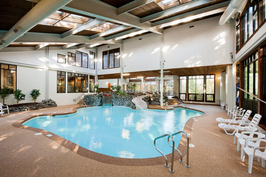 The Summit's indoor pool with a rock waterfall and slide beneath skylights and lounge chairs