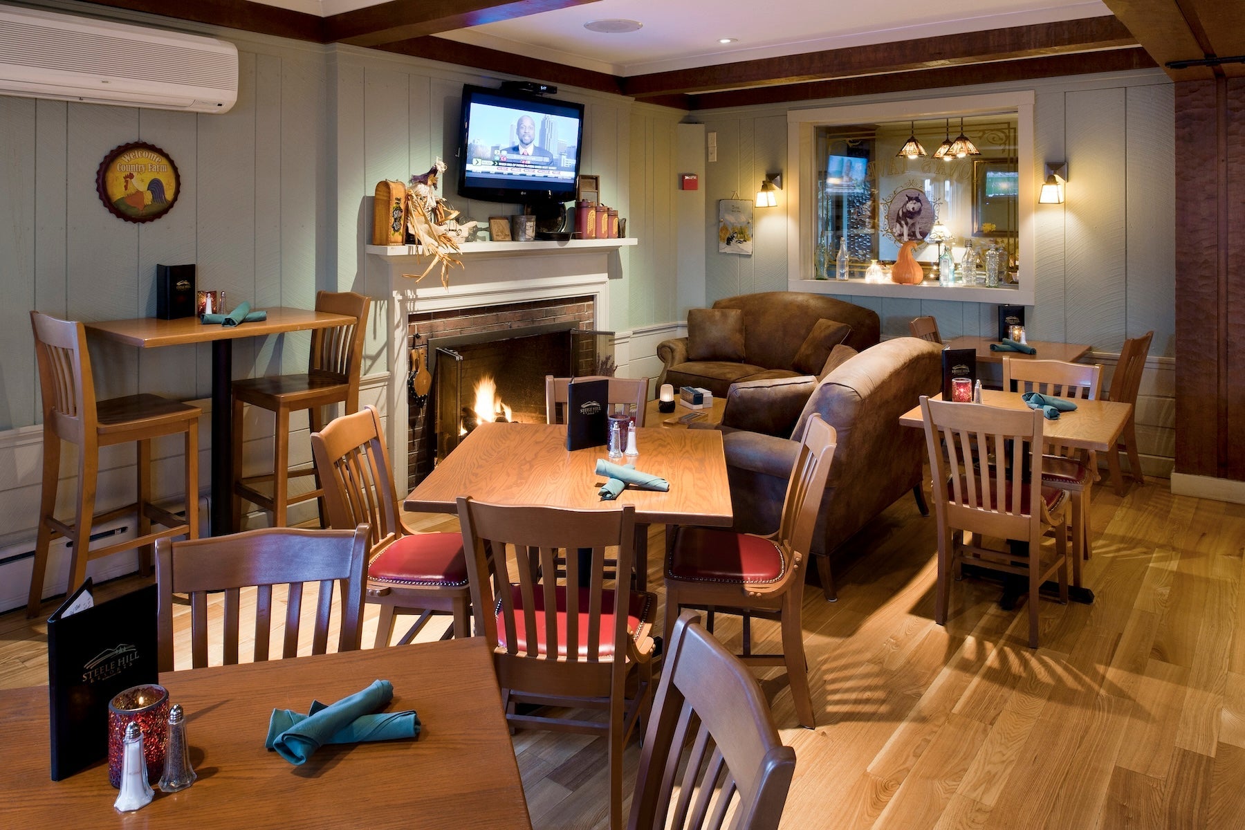 Steele Hill pub lounge with wood tables, leather armchairs and a lit stone fireplace