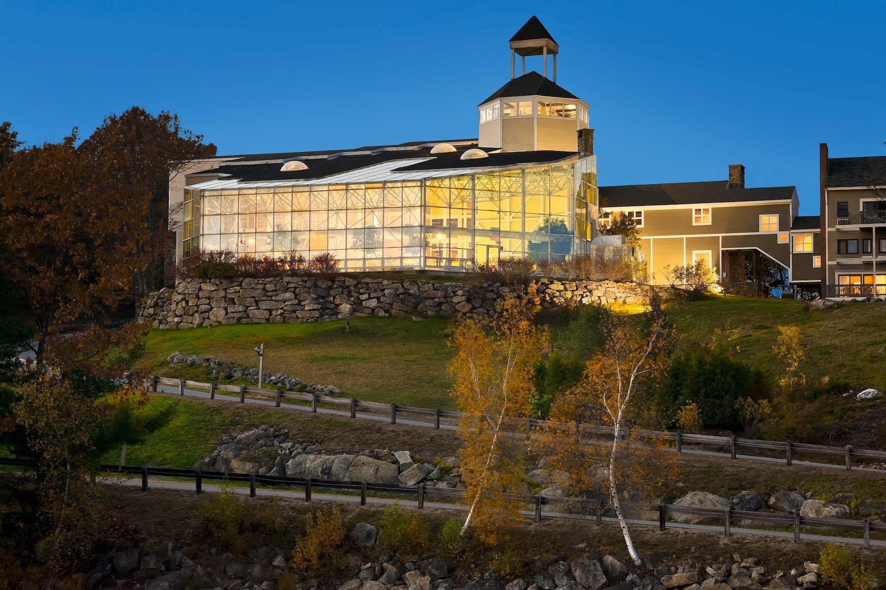 Steele Hill's glass pool atrium glowing at dusk beside the hillside guest wings