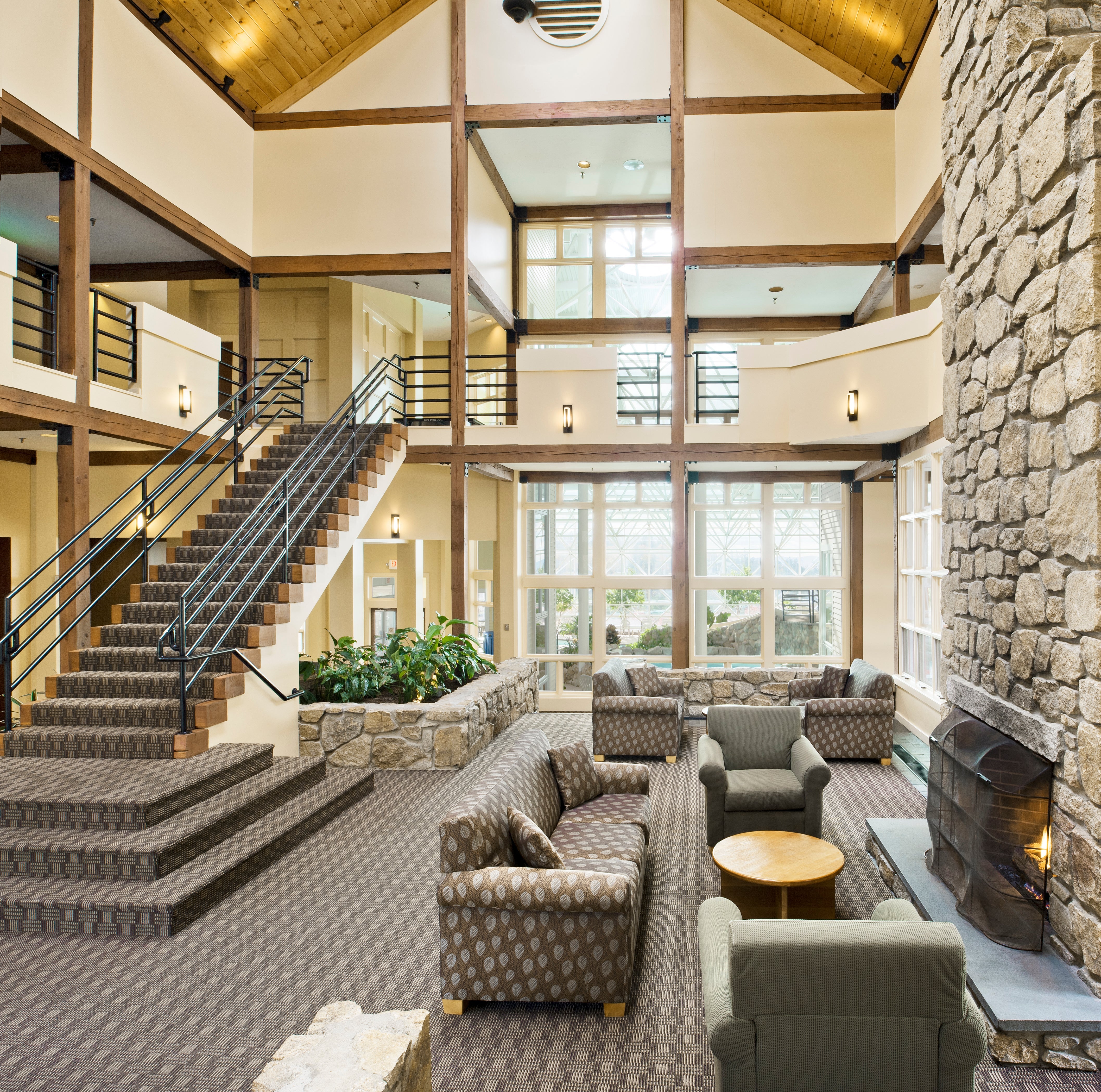 Steele Hill's two-story lobby with exposed timber trusses, sofas and a tall fieldstone fireplace