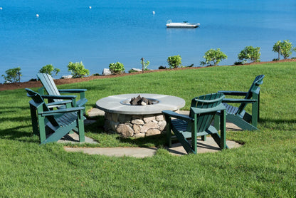 Green Adirondack chairs around a stone fire pit on the Center Harbor Inn lawn at the lake's edge