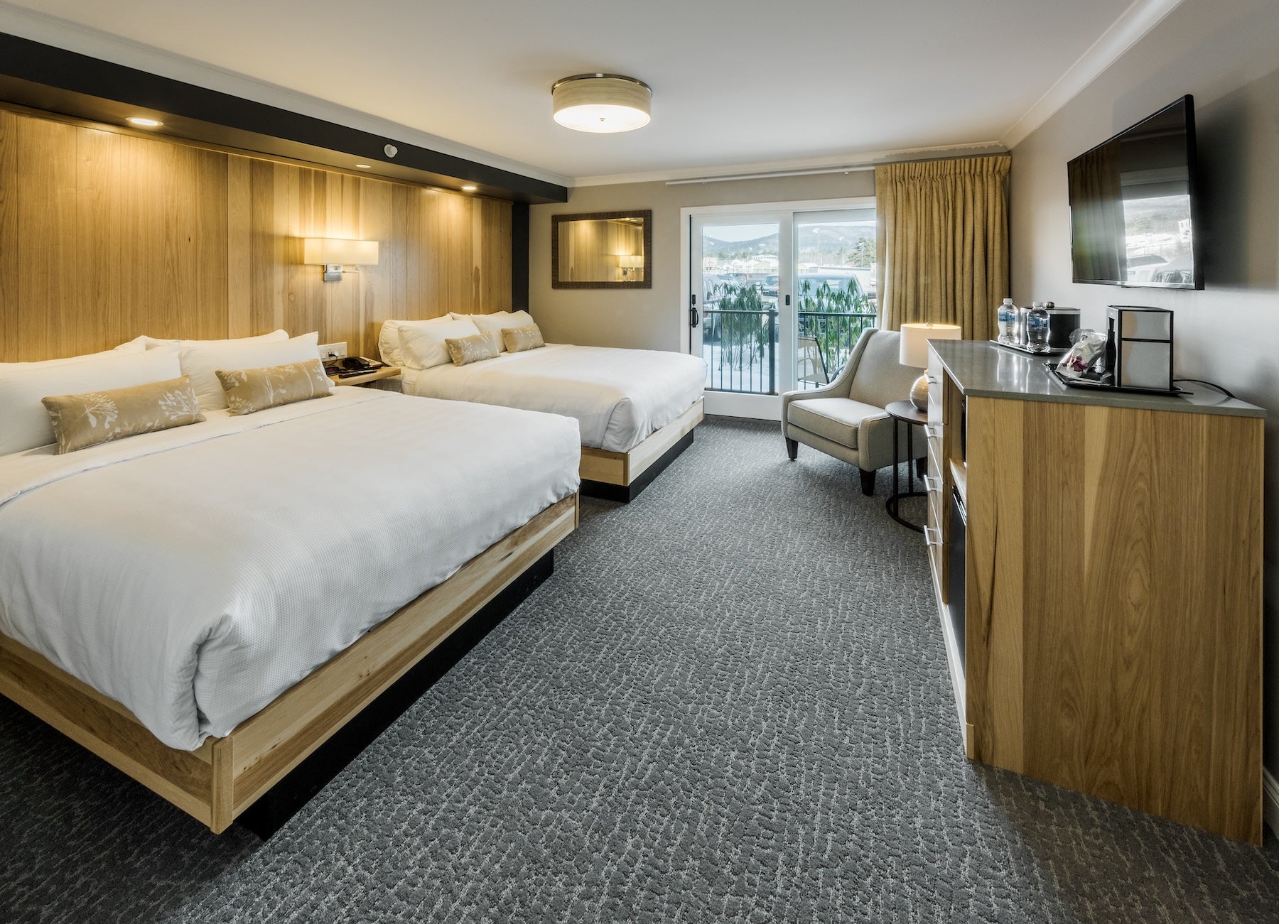 Center Harbor Inn room with two queen beds and a balcony door overlooking the marina