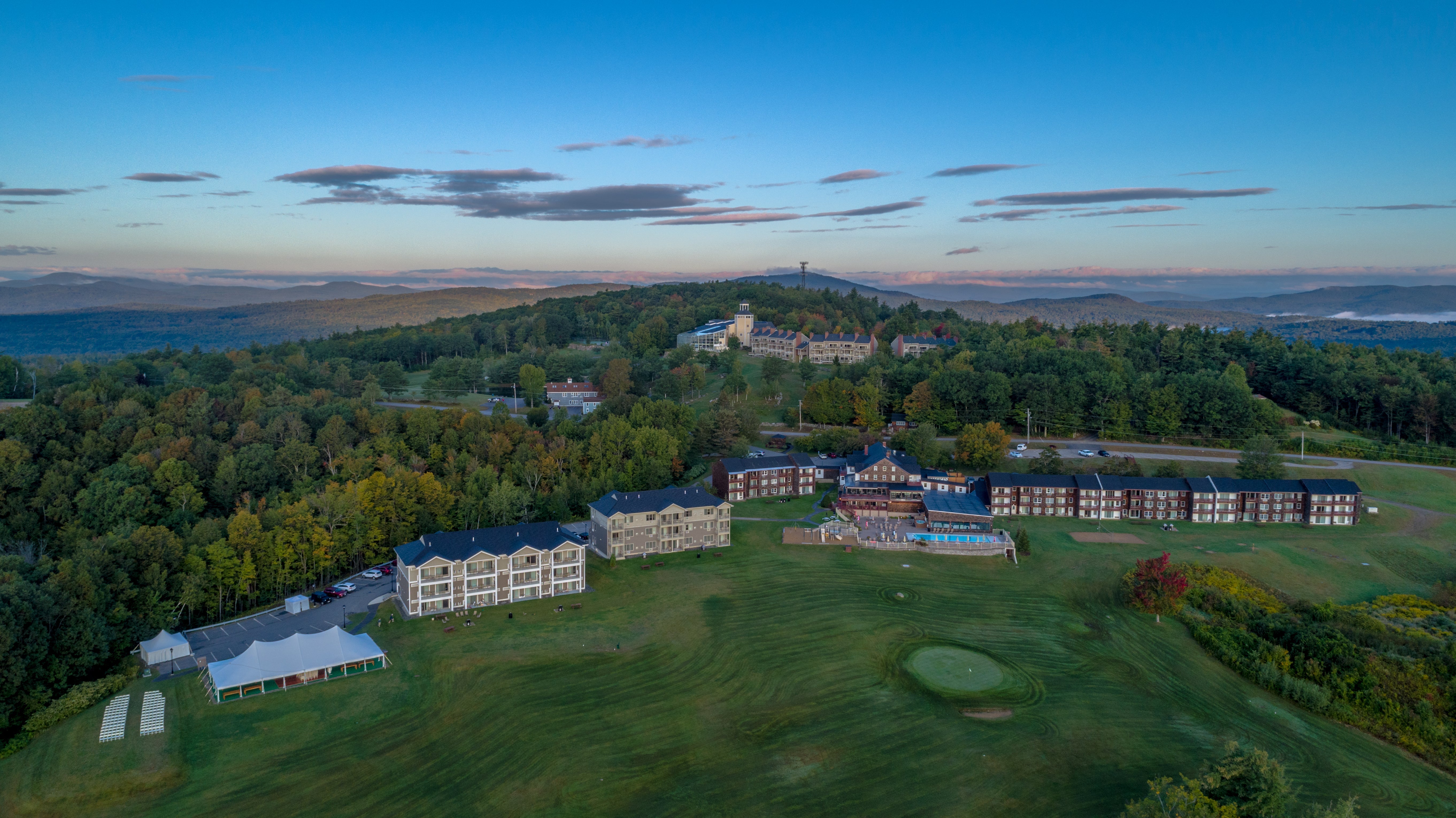 Aerial view at dusk of Steele Hill Resort's guest buildings, pool and golf lawn among wooded ridges