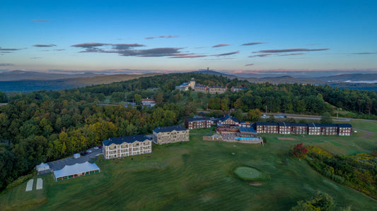 Aerial view at dusk of Steele Hill Resort's guest buildings, pool and golf lawn among wooded ridges