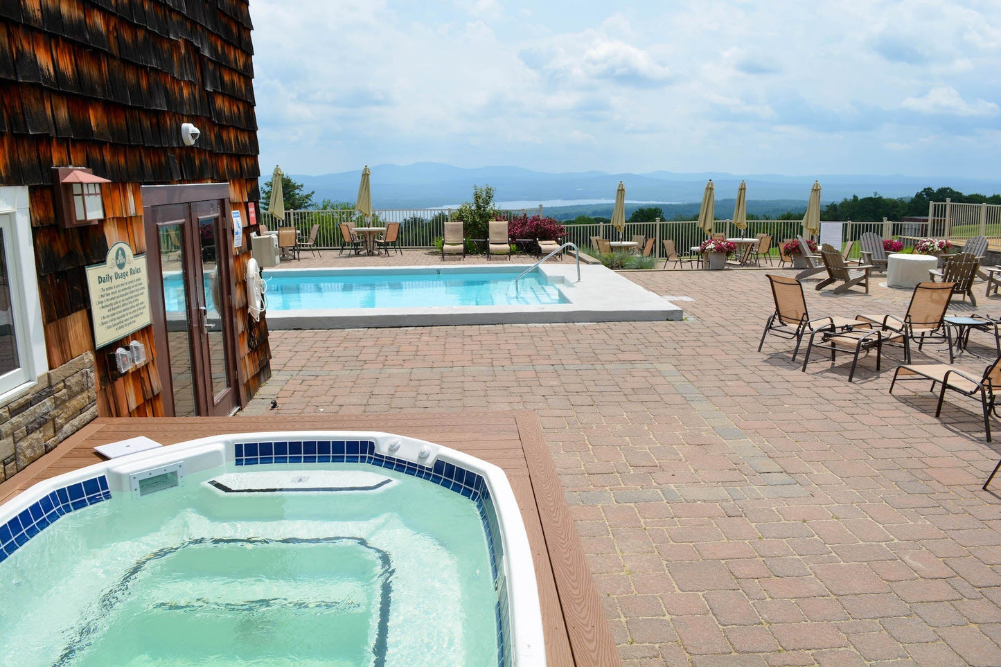 Steaming outdoor hot tub on the Steele Hill patio with a pool and hazy lake and mountain views