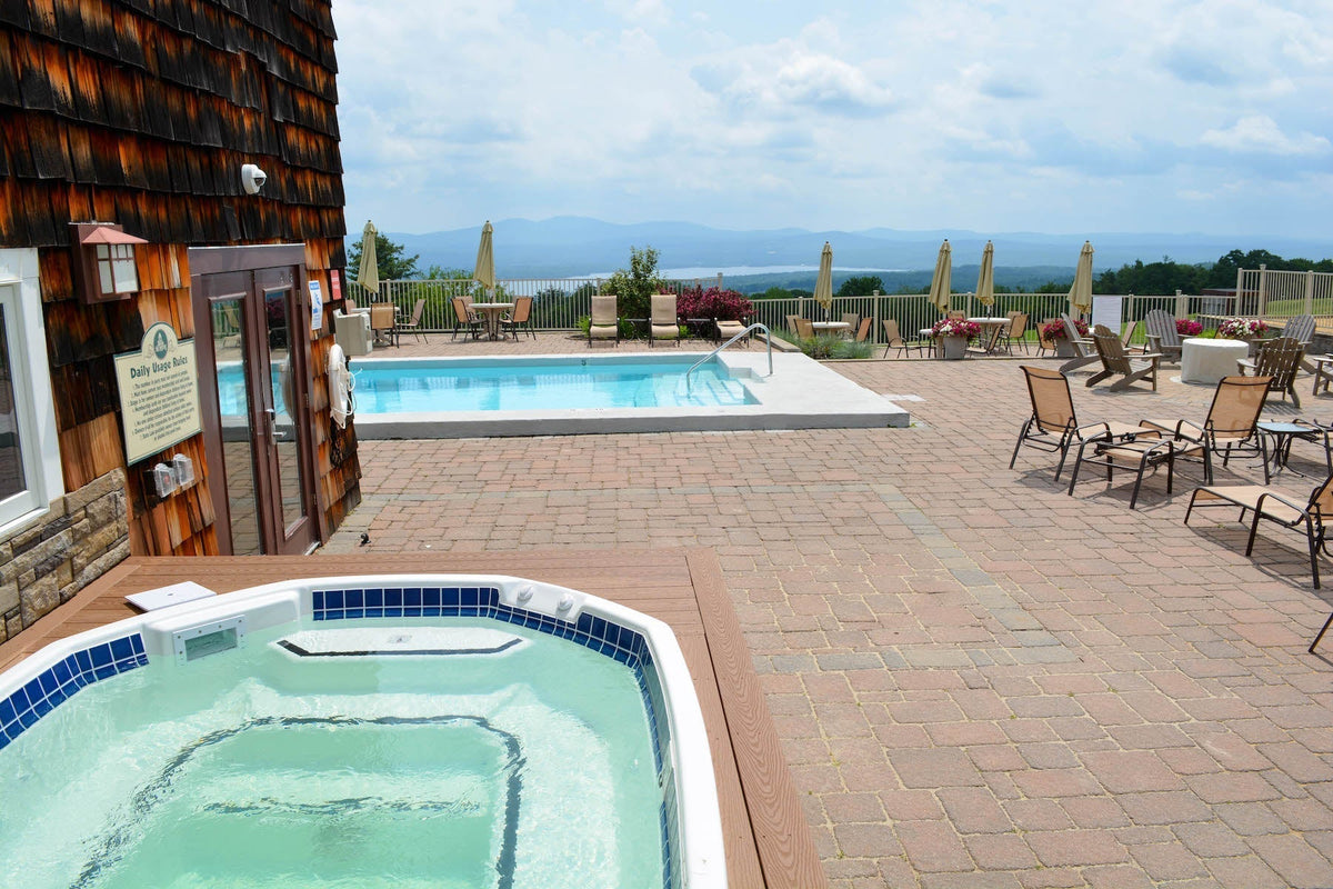 Steaming outdoor hot tub on the Steele Hill patio with a pool and hazy lake and mountain views